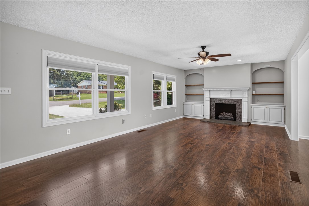 113 Greenfield Avenue Pendleton, SC 29670 - Photo 4 of 40 Rich hardwood floors complement a decorative fireplace flanked by built-in shelving and sun-filled windows.