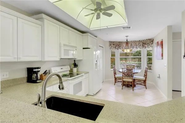 a kitchen with granite countertop a stove a sink a dining table and chairs