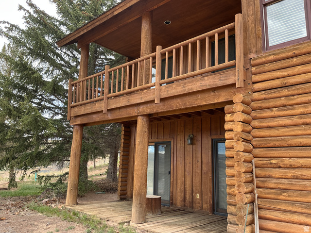 550 State Line Road Manila, UT 84046 - Photo 40 of 41 Log cabin exterior featuring a second-story wood-plank balcony with a matching wood railing, supported by robust log columns