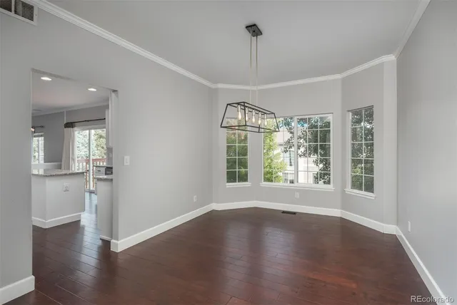 a view of an empty room with wooden floor fridge and a window