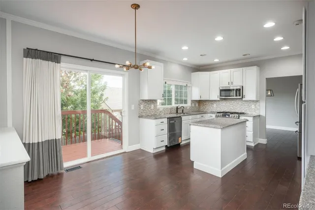 a kitchen with stainless steel appliances granite countertop a refrigerator a sink dishwasher a stove and white cabinets with wooden floor