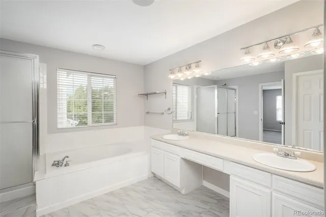 a bathroom with a bathtub a double vanity sink and large mirror