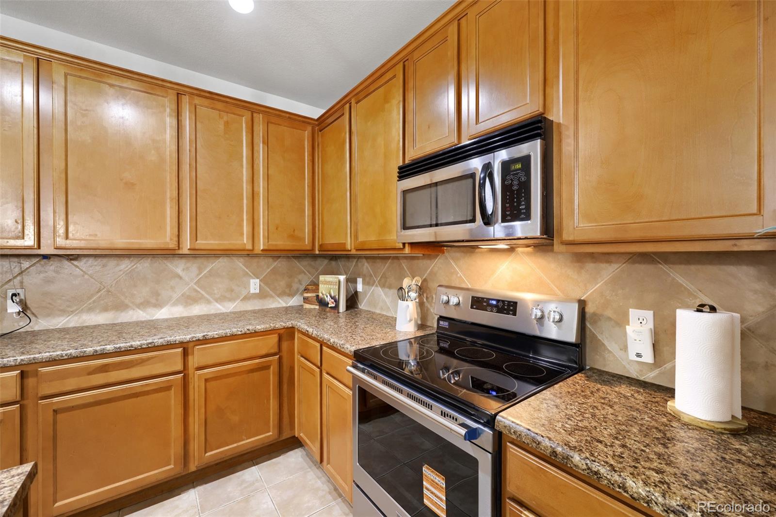 7130 Simms Street, Unit 107 Arvada, CO 80004 - Photo 11 of 29 a kitchen with granite countertop cabinets stainless steel appliances and a sink