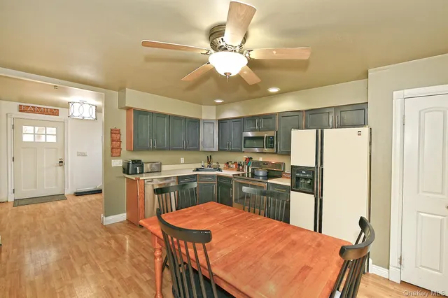 a kitchen with a refrigerator a stove top oven a sink dishwasher with a dining table and chairs