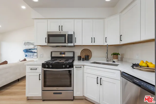 a kitchen with white cabinets and appliances