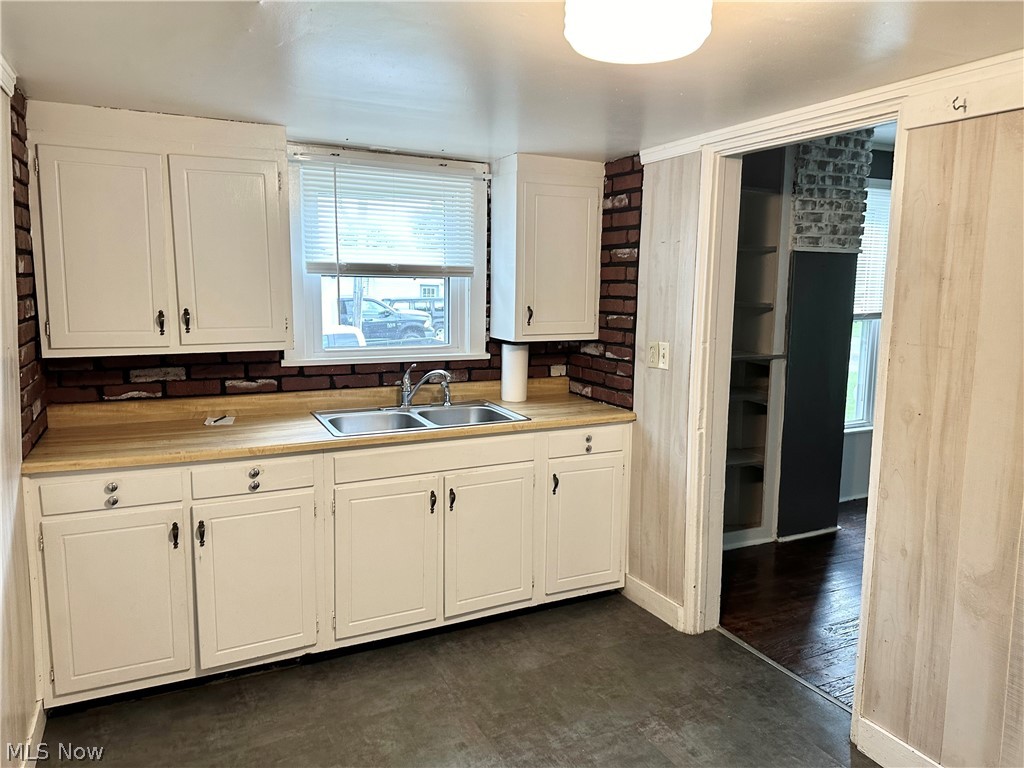 6841 Warren - Sharon Road Brookfield, OH 44403 - Photo 8 of 32 Kitchen featuring sink, white cabinets, brick wall, and dark wood-type flooring