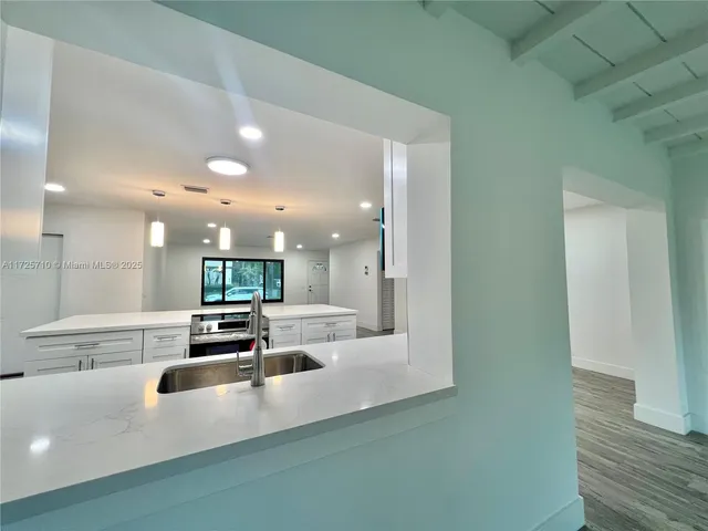 a large kitchen with kitchen island a large counter top space a sink and stainless steel appliances