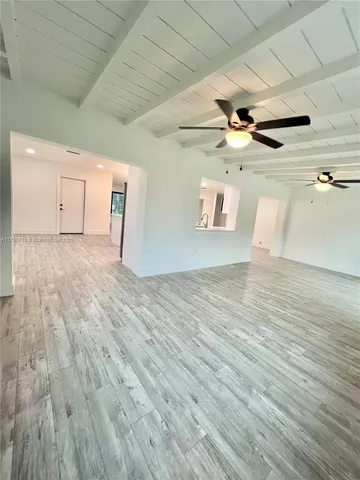 a large white kitchen with a white countertops a stove a dining table and chairs with wooden floor