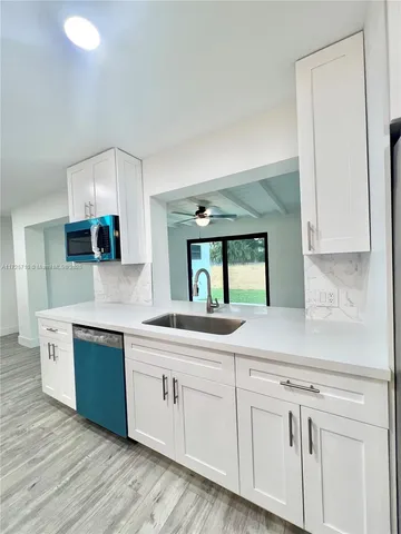 a kitchen with stainless steel appliances granite countertop a sink and cabinets with wooden floor