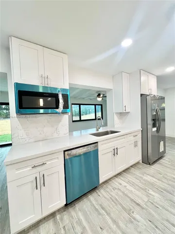 a kitchen with white cabinets and white appliances