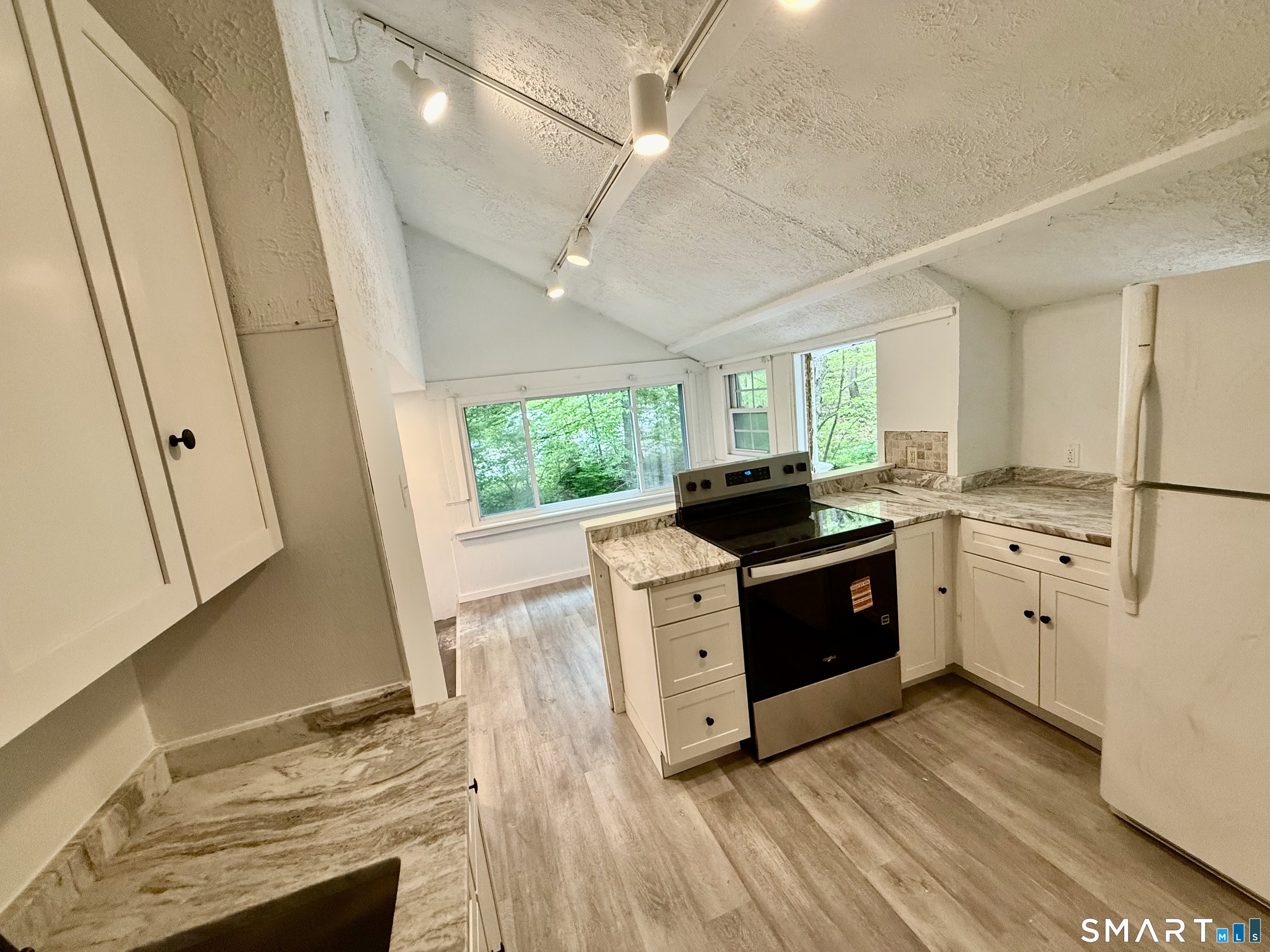 277 Lake Road Andover, CT 06232 - Photo 10 of 18 a kitchen with stainless steel appliances kitchen island granite countertop a stove a sink a refrigerator and a microwave