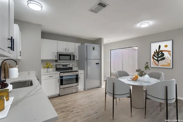 a kitchen with stainless steel appliances kitchen island granite countertop a dining table and chairs with wooden floor