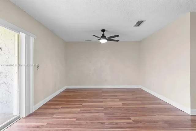 a view of a room with wooden floor and a ceiling fan