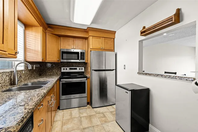 a kitchen with granite countertop a refrigerator and a sink