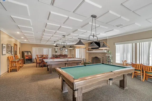 a room with furniture pool table flat screen tv and windows