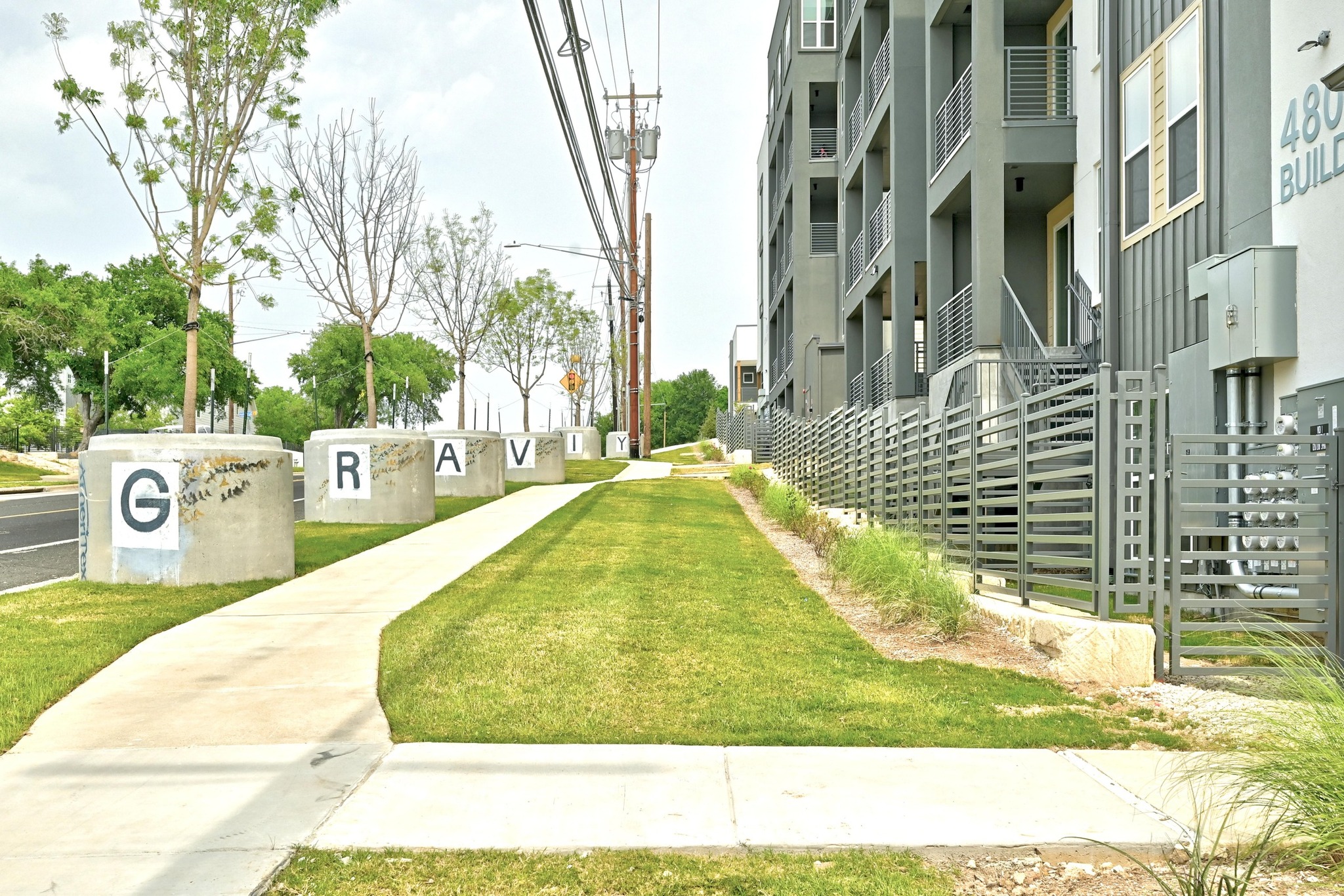 4801 Springdale Road, Unit 2301 Austin, TX 78723 - Photo 35 of 36 A contemporary residential building with a neatly maintained lawn and creative street art along the sidewalk.