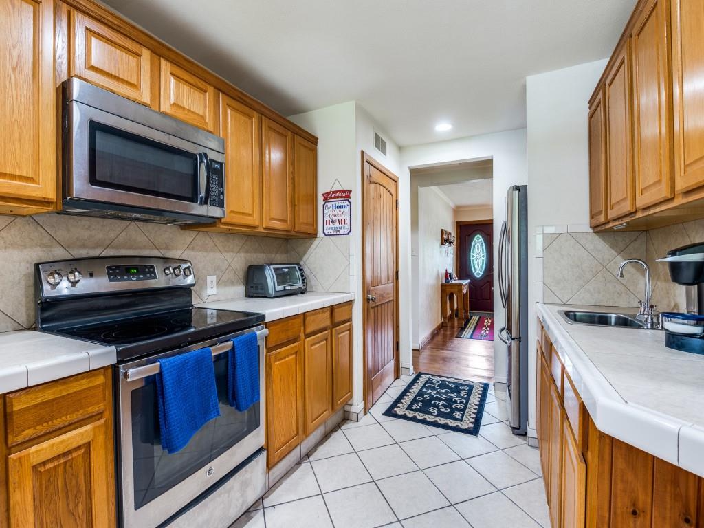 111 County Road 2806 Mabank, TX 75147 - Photo 36 of 40 a kitchen with stainless steel appliances granite countertop a stove top oven a sink dishwasher and a microwave oven on the blue kitchen countertops