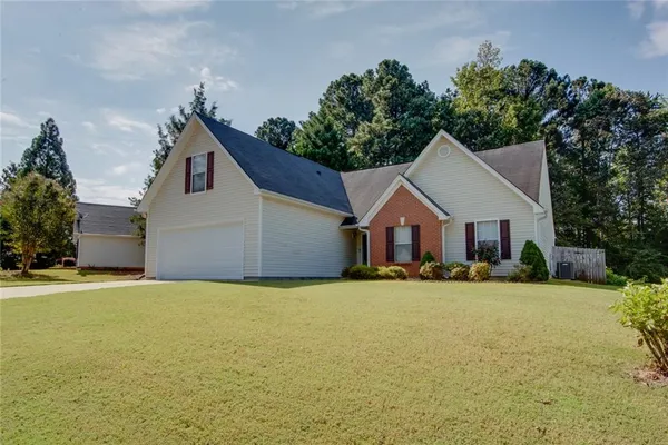 a front view of house with yard and trees in the background