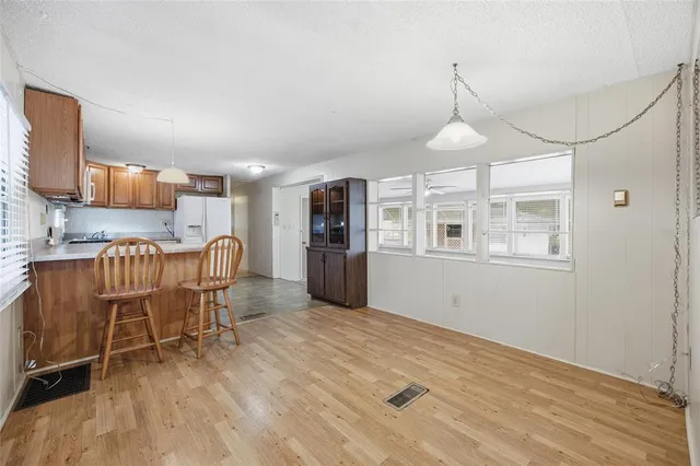 a view of a kitchen with a dining table chairs wooden floor and a window
