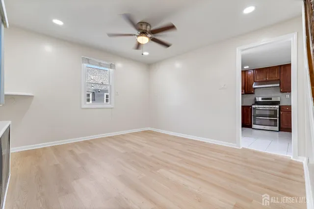 an empty room with wooden floor closet and windows