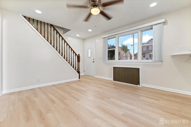a view of empty room with wooden floor and fan
