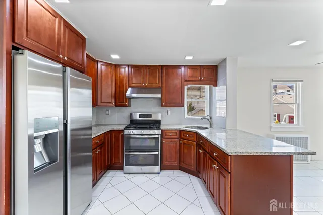 a large kitchen with stainless steel appliances granite countertop a refrigerator and a stove top oven