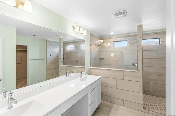 a bathroom with a double vanity sink mirror and shower