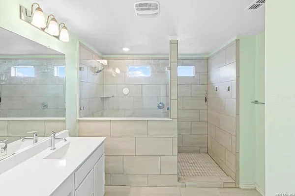 a bathroom with a shower sink and mirror