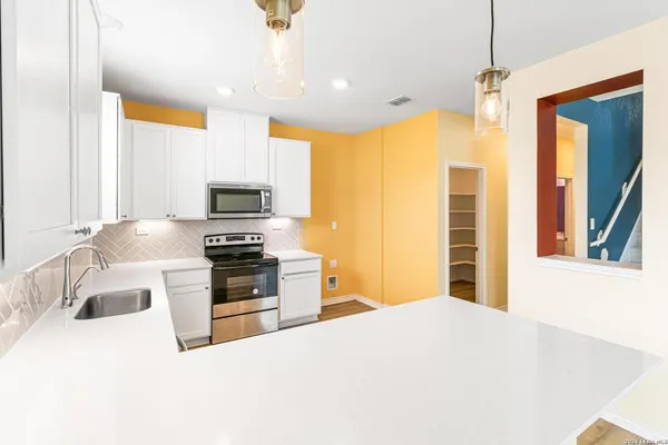 a kitchen with stainless steel appliances a stove a sink and a refrigerator with wooden floor