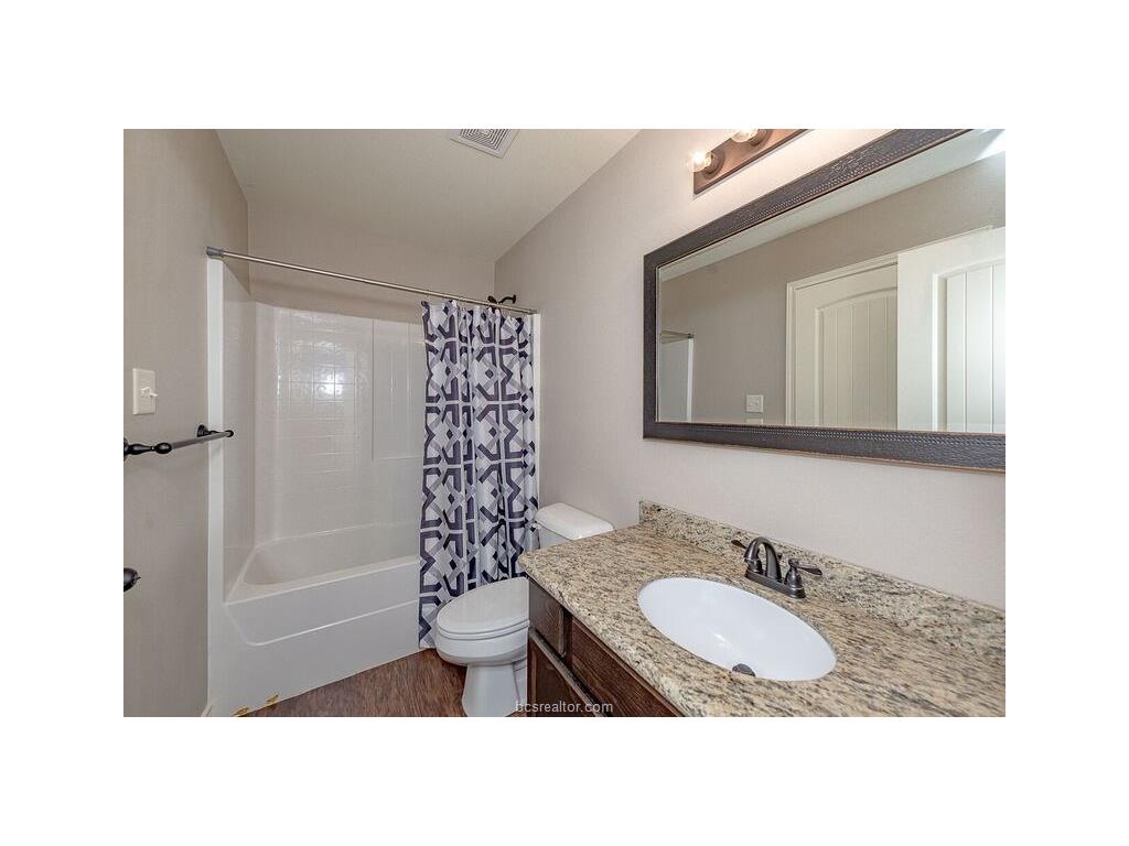 131 Watson Lane Bryan, TX 77801 - Photo 18 of 20 Full bathroom featuring vanity, hardwood / wood-style floors, shower / bathtub combination with curtain, and toilet