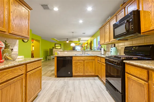 a kitchen with stainless steel appliances granite countertop wooden cabinets a stove top oven a sink and dishwasher