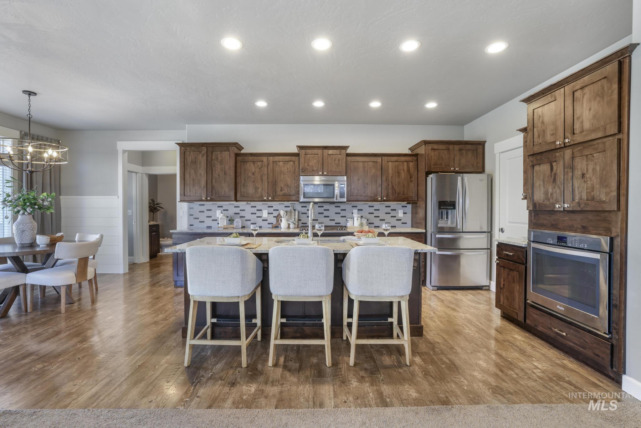 2858 Sunray Loop Twin Falls, ID 83301 - Photo 10 of 45 Kitchen featuring a breakfast bar area, stainless steel appliances, an island with sink, light stone counters, and light wood finished floors