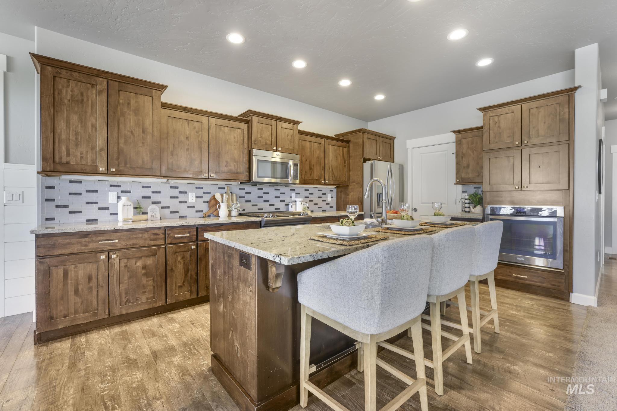 2858 Sunray Loop Twin Falls, ID 83301 - Photo 11 of 45 Kitchen featuring backsplash, a breakfast bar area, a kitchen island with sink, light wood-style floors, and recessed lighting