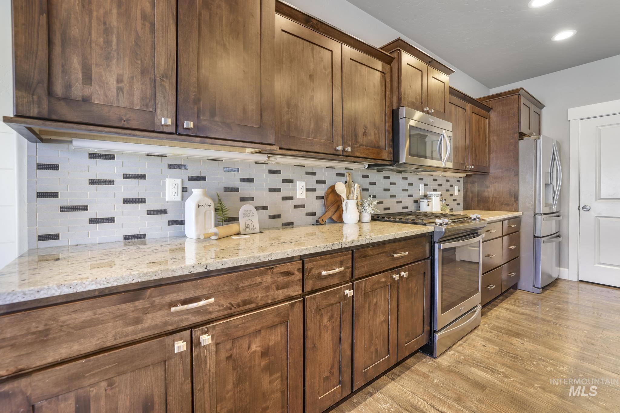 2858 Sunray Loop Twin Falls, ID 83301 - Photo 12 of 45 Kitchen with appliances with stainless steel finishes, backsplash, light stone counters, light wood-style flooring, and recessed lighting