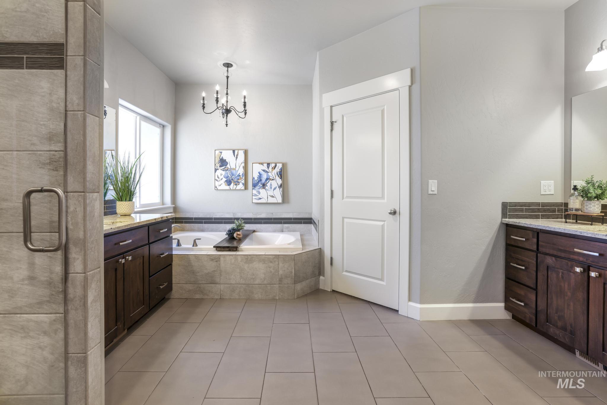 2858 Sunray Loop Twin Falls, ID 83301 - Photo 18 of 45 Bathroom with vanity, a bath, a stall shower, light tile patterned flooring, and a chandelier