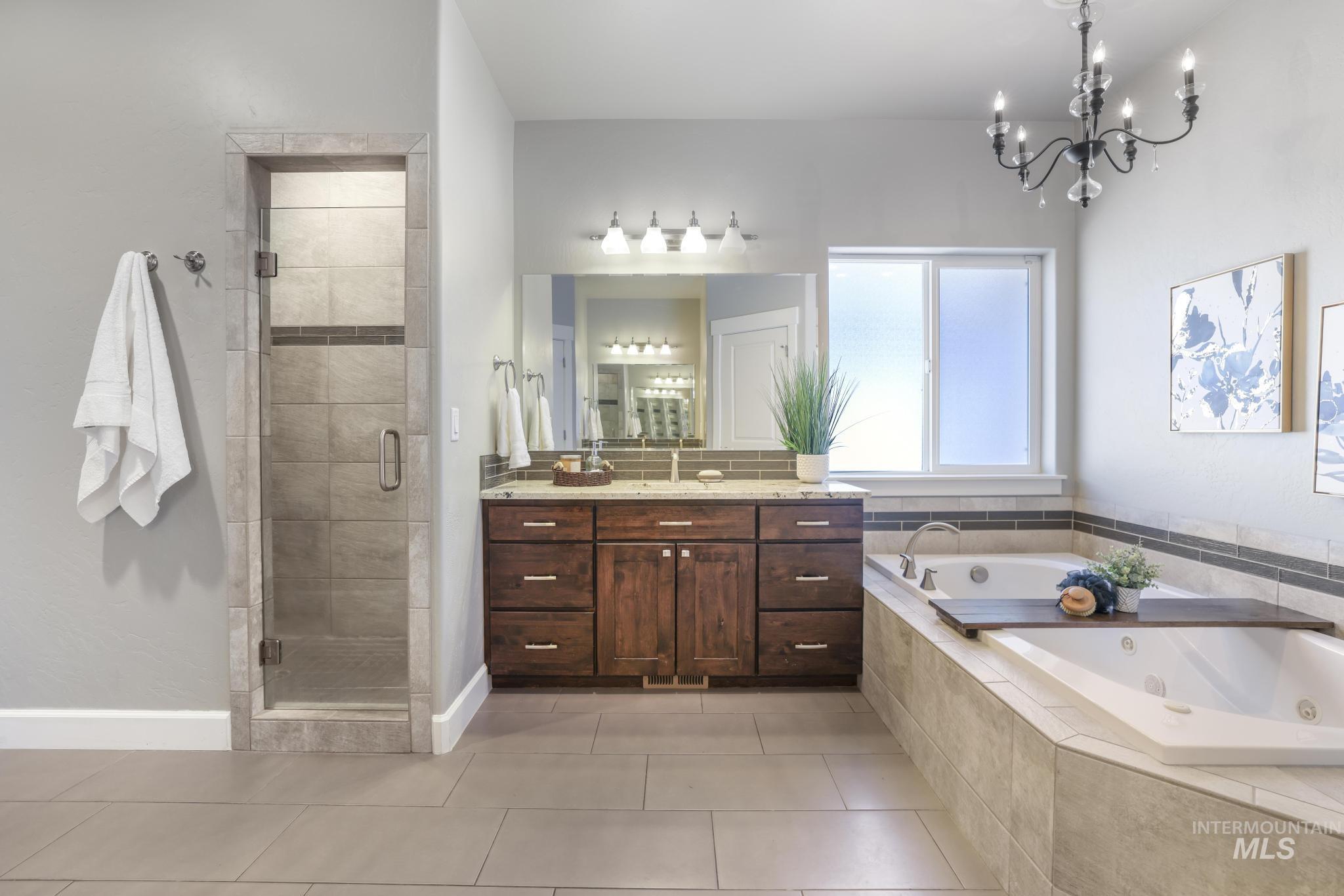 2858 Sunray Loop Twin Falls, ID 83301 - Photo 19 of 45 Bathroom with a whirlpool tub, vanity, a stall shower, light tile patterned flooring, and a chandelier