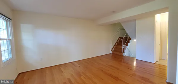 a view of an empty room with wooden floor and stairs