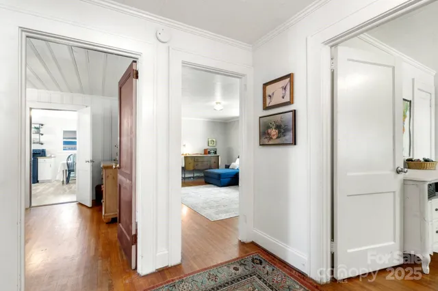 a view of a hallway with wooden floor and living room