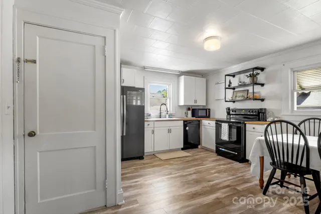 a kitchen with a refrigerator a sink dishwasher a dining table and chairs with wooden floor