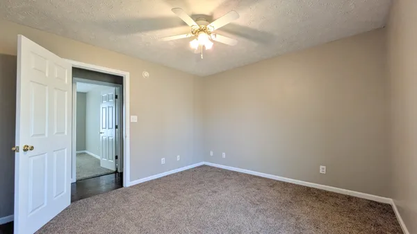 an empty room with a chandelier fan and windows