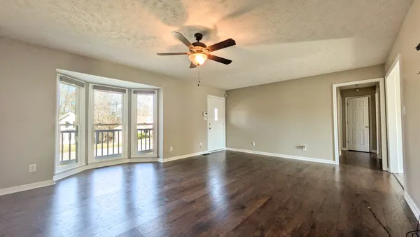 a view of an empty room with window and wooden floor