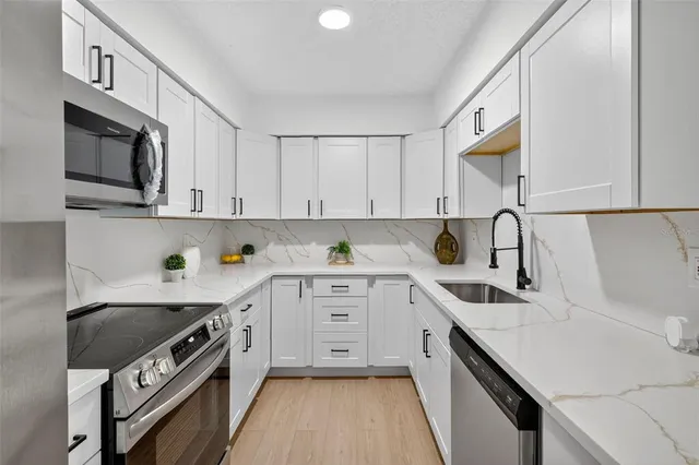 a kitchen with stainless steel appliances a sink stove top oven and cabinets