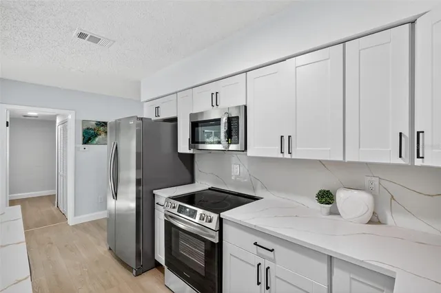 a kitchen with stainless steel appliances white cabinets and a refrigerator