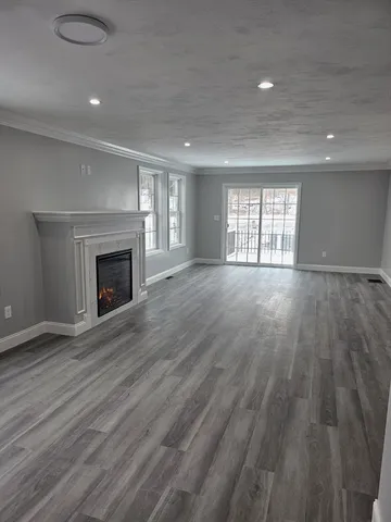 an empty room with wooden floor fireplace and windows