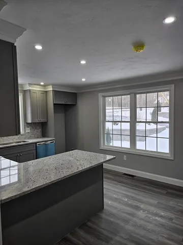 a living room with hard wood floors and a kitchen