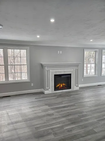 an empty room with wooden floor fireplace and windows