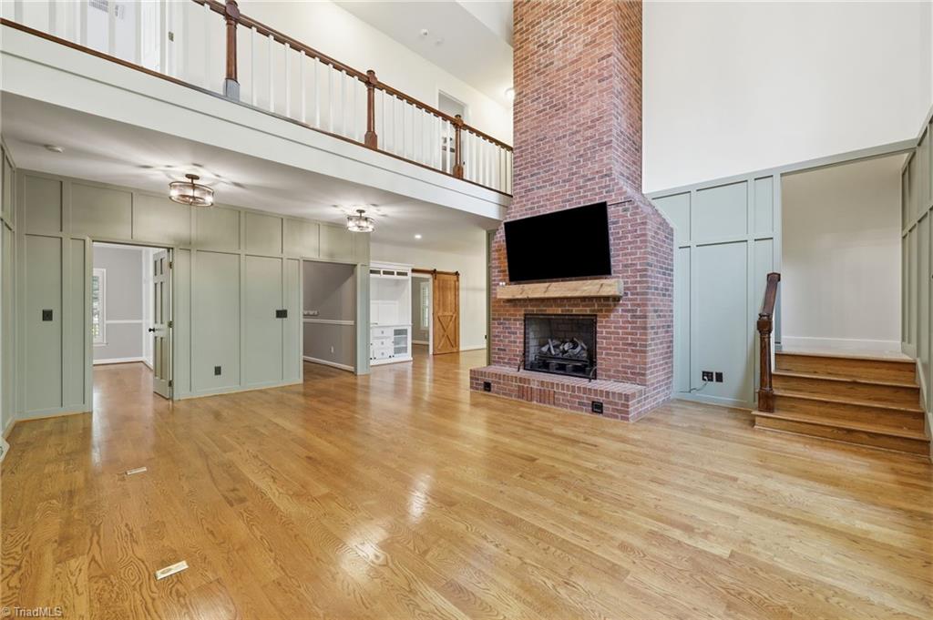 8861 Boylston Road Colfax, NC 27235 - Photo 17 of 50 Vaulted ceilings, a soaring brick fireplace, and an open second-story gallery create a dramatic gathering space, while the private entrance to the main-level primary suite is thoughtfully positioned just off the great room.
