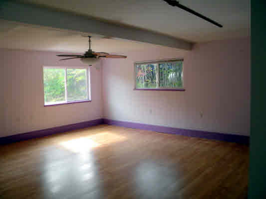 6392 Kalama Road, Unit 4 Kapaa, HI 96746 - Photo 21 of 24 an empty room with wooden floor chandelier fan and windows