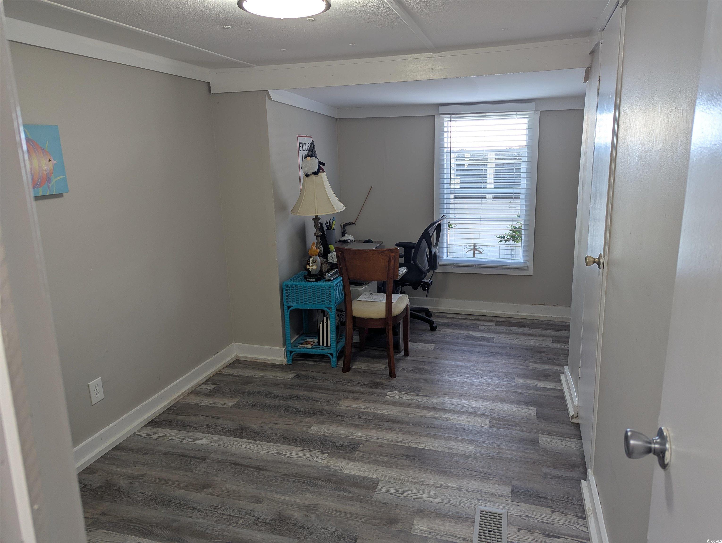 Office space with dark wood-style flooring and baseboards