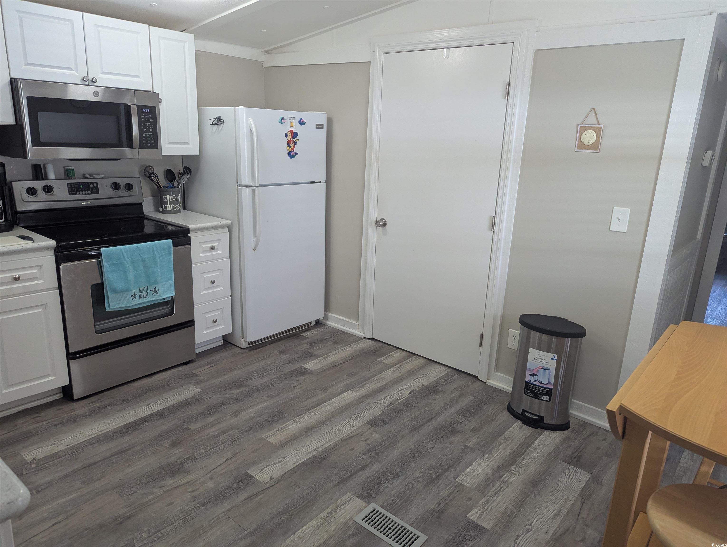 148 Offshore Drive Murrells Inlet, SC 29576 - Photo 10 of 18 Kitchen featuring appliances with stainless steel finishes, light countertops, white cabinets, dark wood-style floors, and lofted ceiling